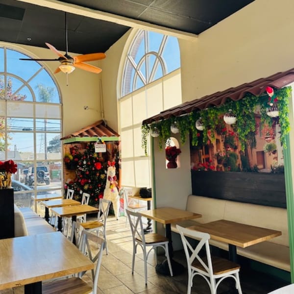 Bright, empty Best Artisan Empanadas dining room with light wood tables, white chairs, and arched windows.